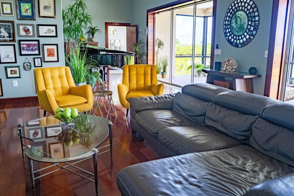 Un salon moderne avec un canapé gris, des fauteuils jaunes et une table basse en verre.