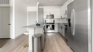 A modern kitchen with stainless steel appliances, a central island, and white cabinetry.