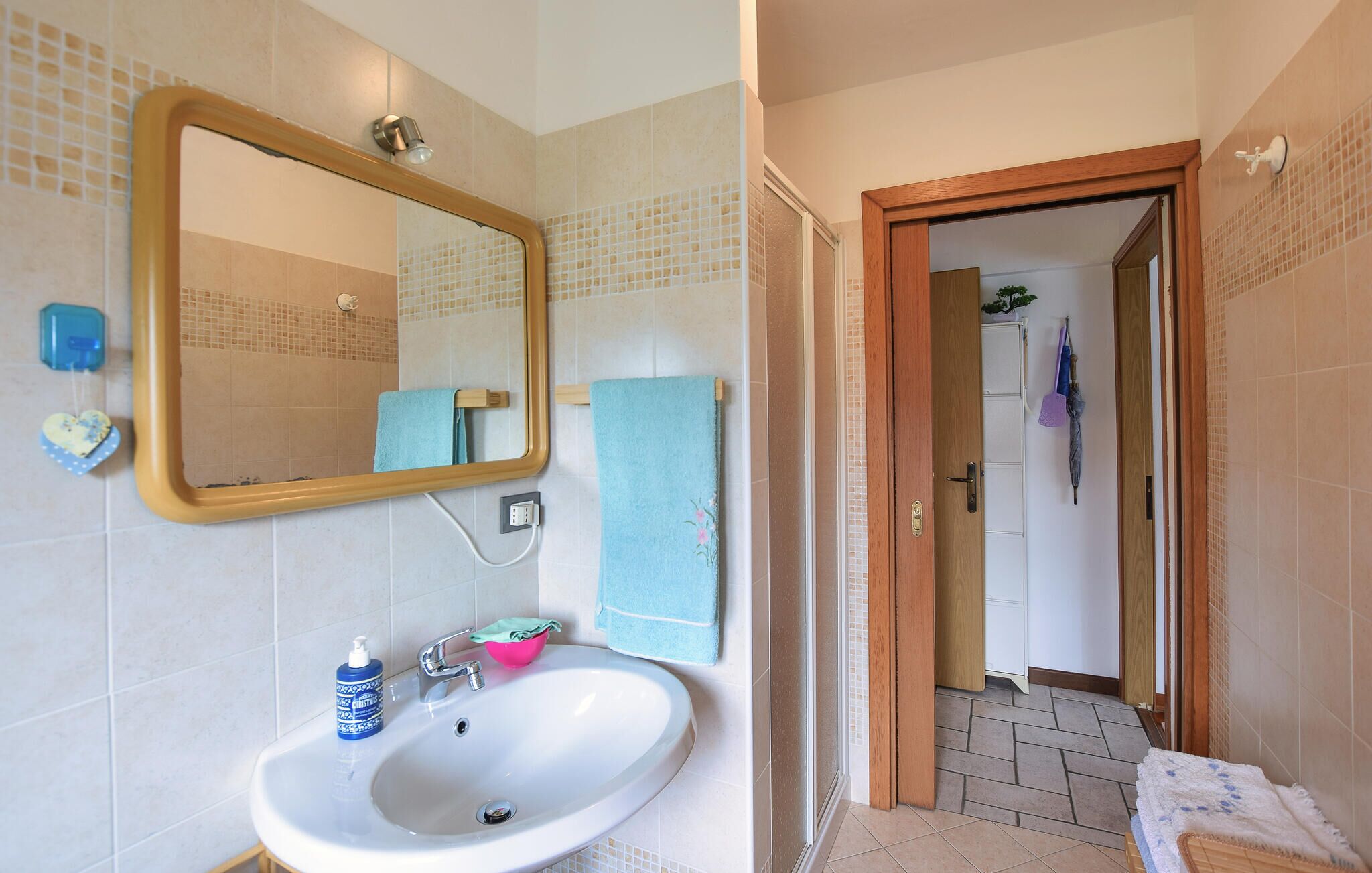 Een badkamer met een wastafel, spiegel en douche.