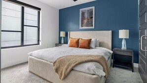 A bedroom with a large bed, two nightstands, a window, and a framed picture on the wall. - Landing | Spectacular 1BD, Clubhouse, Pool (Buckhead)