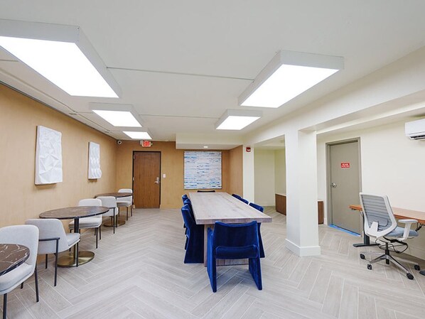 A conference room with a long table, blue chairs, and a whiteboard on the wall.