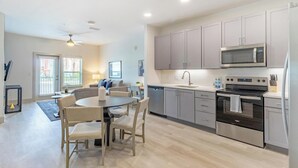 Cocina moderna con gabinetes grises, estufa negra y microondas. Cuenta con una zona de comedor con una mesa redonda y sillas.