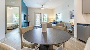 Una sala de estar moderna con una mesa redonda, sofás y una cocina con lavavajillas.