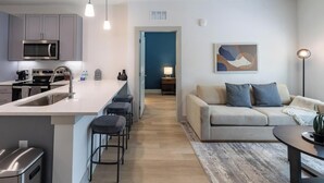 A modern kitchen with a central island, bar stools, and a dining area with a table and chairs. - Landing | Incredible 1BD, Gym, Yoga Studio (Santa Rosa Beach)