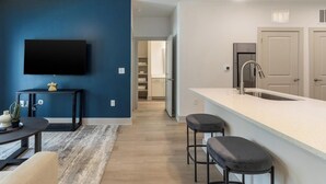 A modern kitchen with a white countertop, stainless steel sink, and bar stools. - Landing | Incredible 1BD, Gym, Yoga Studio (Santa Rosa Beach)