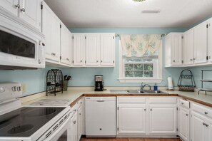 A kitchen with white cabinets, a microwave, a coffee maker, and a dishwasher.