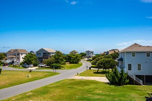 A residential street with houses, a driveway, and a clear blue sky.