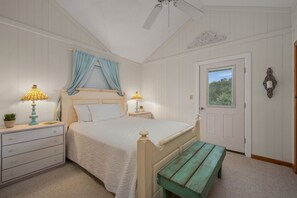 A bedroom with a bed, bedside tables, a bench, a ceiling fan, and a door with a window. - "Ehh, What's up, Duck?": Private Pool, Dog-Friendly, Short Walk to Beach Access (Duck)
