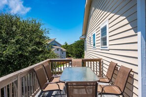 A deck with a table and chairs, overlooking a residential area with houses and trees.