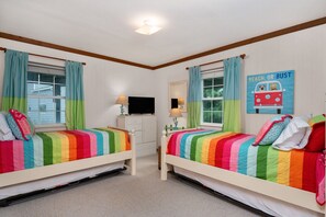 A bedroom with two beds, a desk, and a TV.