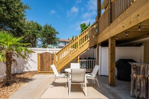 A wooden deck with a staircase, outdoor seating, and a barbecue area.