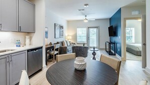 A modern kitchen with grey cabinets, a dishwasher, and a dining area with a round table and chairs.