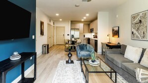 A modern living room with a sofa, a glass coffee table, and a TV mounted on the wall.
