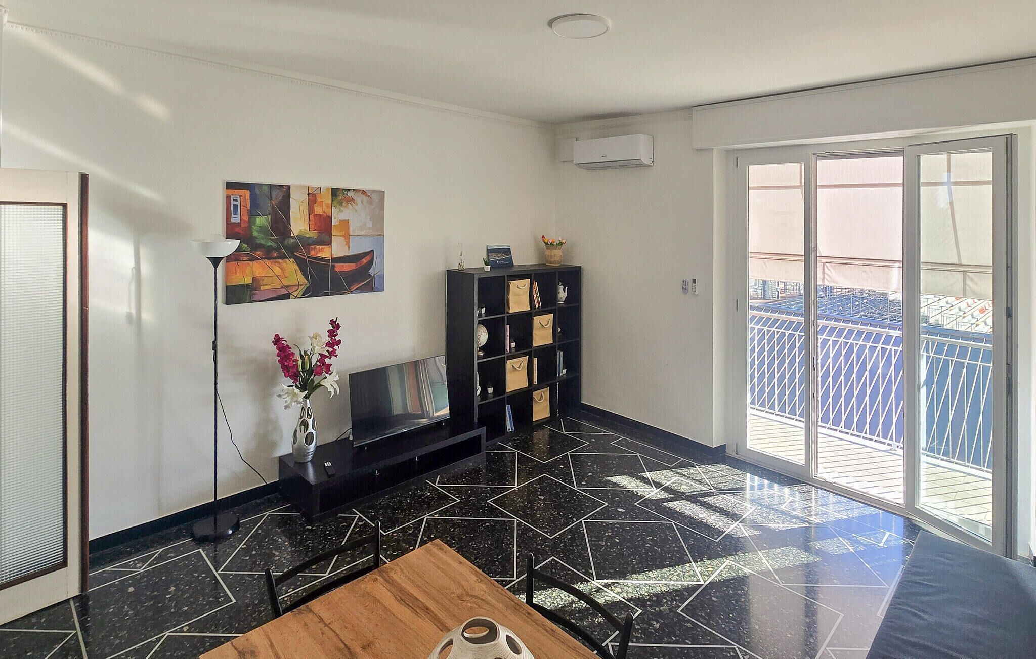 A living room with a black and white tiled floor, a wooden coffee table, a TV, a bookshelf, and a painting on the wall.