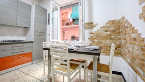 A modern kitchen with white cabinets, a gas stove, and a dining area with white chairs and a table set for four.