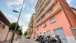 A multi-story residential building with balconies, parked motorcycles, and a street lamp.