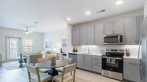A modern kitchen with grey cabinets, a stainless steel microwave, and a black oven.