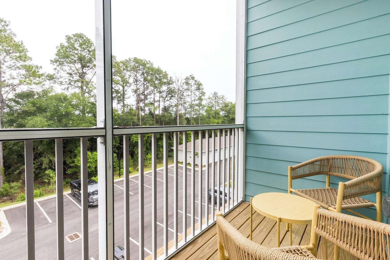 A balcony with a view of a parking lot and trees.