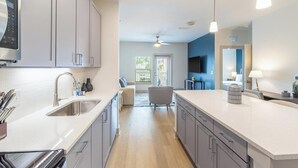 A modern kitchen with a central island, grey cabinets, and stainless steel appliances. - Landing | Spectacular 2BD, Pool, Yoga Studio (Santa Rosa Beach)