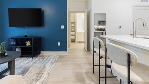 A modern living room with a flat-screen TV, a black entertainment unit, and a blue accent wall.