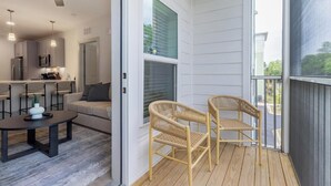 A modern interior with a kitchen, dining area, and a balcony with wicker chairs.