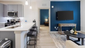 Une cuisine moderne dotée d’un îlot central, de tabourets de bar, d’un four à micro-ondes et d’une cuisinière.