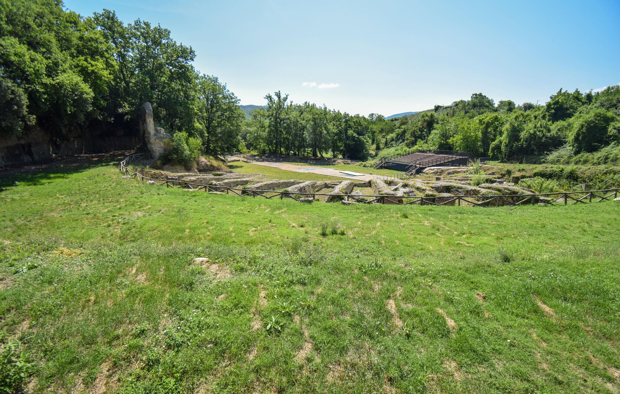 An archaeological site with ancient ruins and a grassy field.