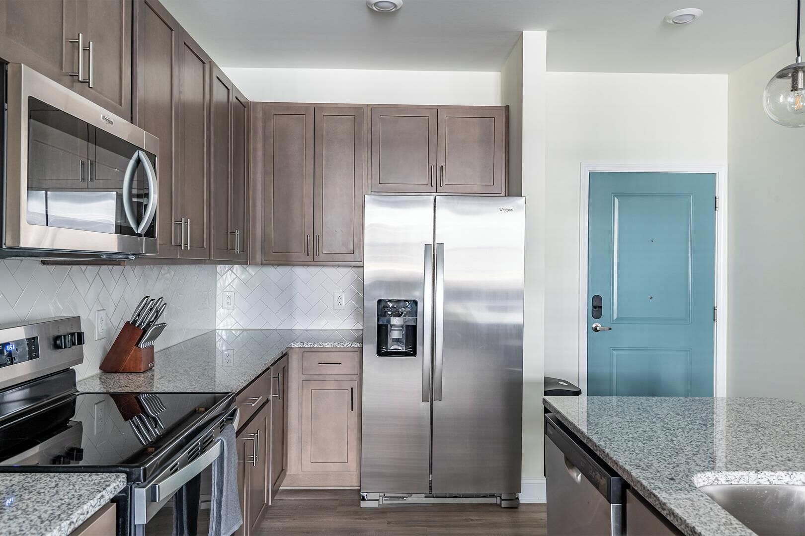 Una cocina moderna con electrodomésticos de acero inoxidable, armarios de madera y una puerta azul.