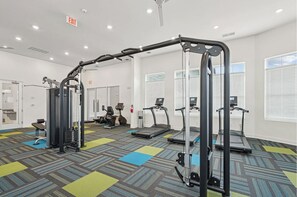 Un gimnasio con cintas de correr, una máquina de pesas y una barra para dominadas.