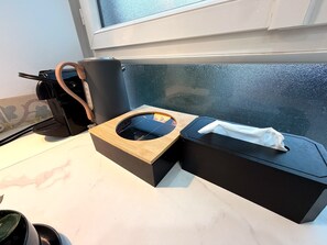 A kitchen counter with a coffee machine, a tissue box, and a trash bin.