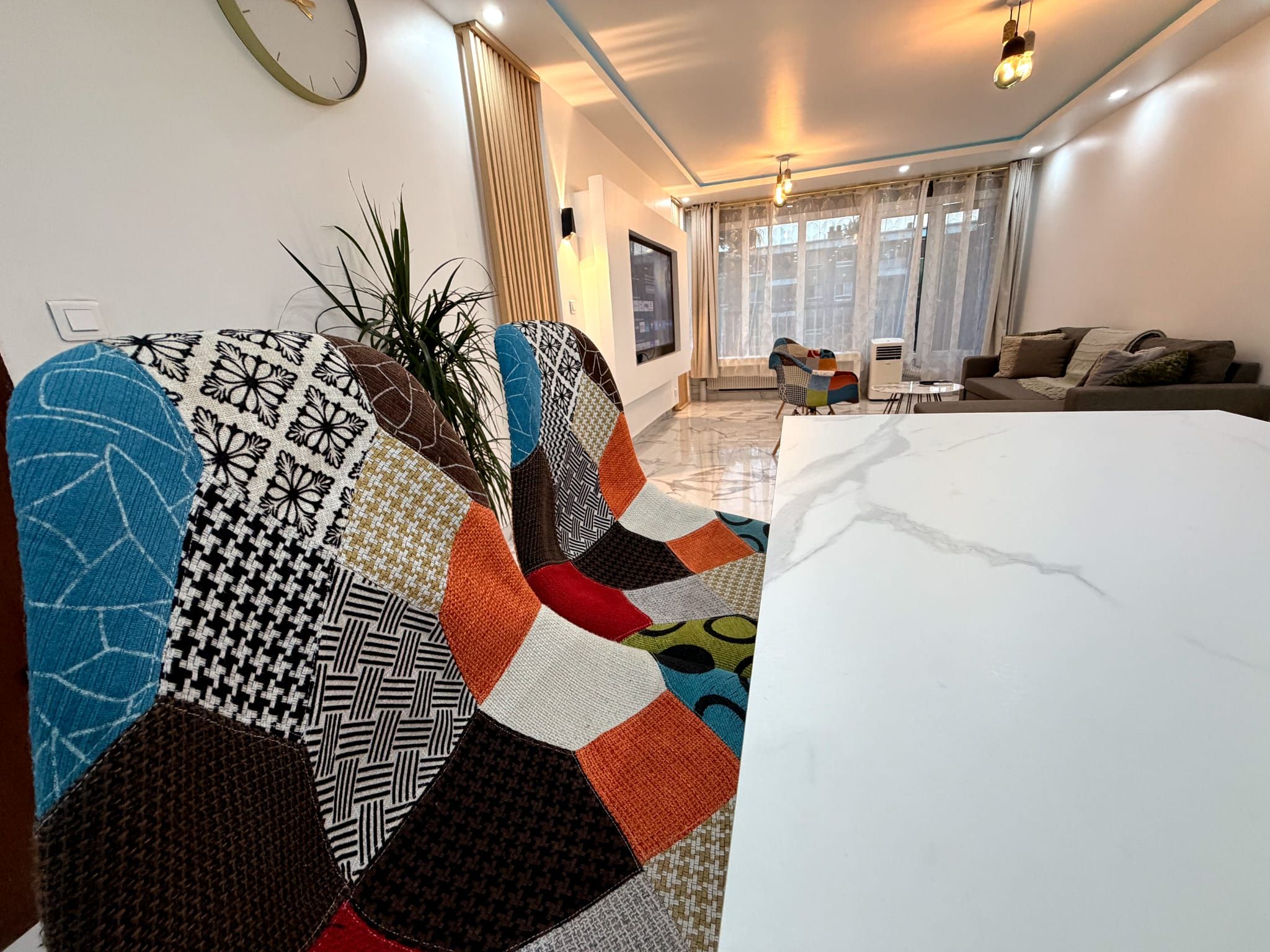 Un salon moderne avec une grande table en marbre blanc, un tapis coloré à motifs et un canapé.