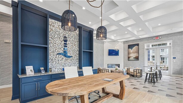 Un moderno vestíbulo de hotel con una gran mesa de madera, armarios azules y una pared de mosaicos.