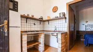 A compact kitchen with a built-in brick oven, a sink, and a stove.