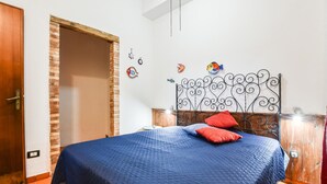 A bedroom with a bed, a wooden door, a brick wall, and a metal headboard.
