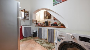 A compact kitchen with a washing machine, a stove, and a small dining area. - 2 bedroom stunning home in Capaci (Capaci)