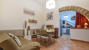 A cozy living room with a sofa, dining table, and chairs. There is a kitchen visible through an archway. - 2 bedroom stunning home in Capaci (Capaci)