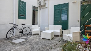 A courtyard with wicker furniture, a bicycle, and a green door. - 2 bedroom stunning home in Capaci (Capaci)