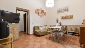 A living room with a sofa, dining table, chairs, a TV, and artwork on the walls. - 2 bedroom stunning home in Capaci (Capaci)