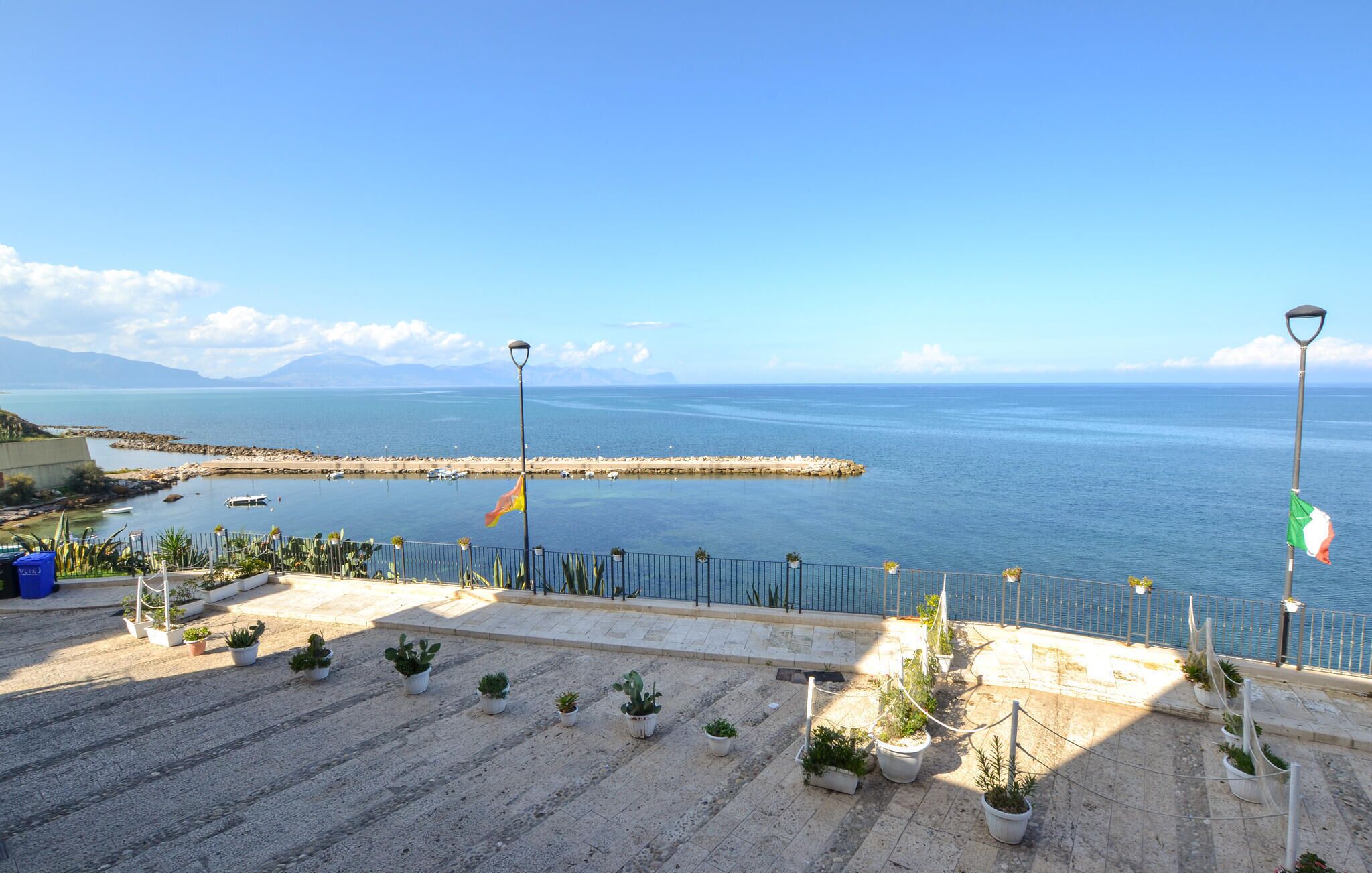 Une promenade en bord de mer agrémentée de plantes en pot et offrant une vue sur la mer.