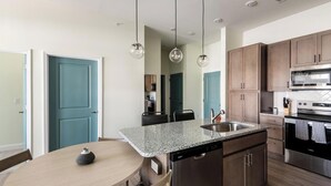 Una cocina moderna con encimeras de granito, electrodomésticos de acero inoxidable y armarios de madera.