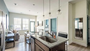 Una cocina moderna con encimeras de granito, una isla central e iluminación colgante.