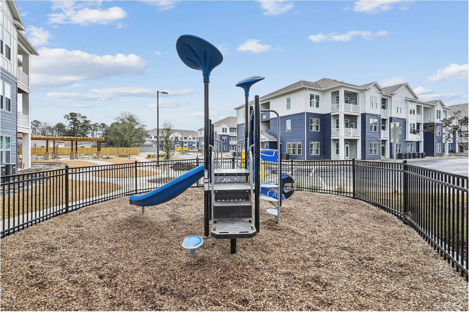 A playground with a slide, climbing structures, and a fenced area.