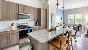 A modern kitchen with granite countertops, stainless steel appliances, and wooden cabinets. - Landing | Modern 1BD, Clubhouse, Gym (Leland)