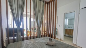 A bedroom with a bed, curtains, a TV, and a view of the dining area. - La Terrasse du Gosier (Le Gosier)