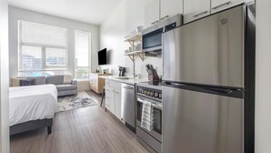 A modern kitchen with stainless steel appliances, a built-in oven, and a flat-screen TV above the counter. - Landing | Amazing Studio, Clubhouse, Gym (Denver)