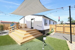 Ein Mobilheim mit einer Veranda, Stufen und einer Fahnenstange mit der amerikanischen Flagge.
