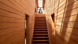 A wooden interior with a central staircase, a fire extinguisher, and a skylight. - Palafito Azul Apart Hotel (Castro)