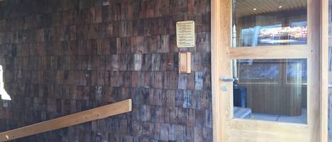 A wooden door with a glass panel, a wooden wall with a textured pattern, and a metal handrail.