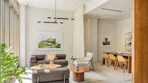 A modern living room with a sofa, armchairs, a coffee table, and a dining area with chairs and a table.