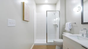 A modern bathroom with a shower, toilet, and sink.